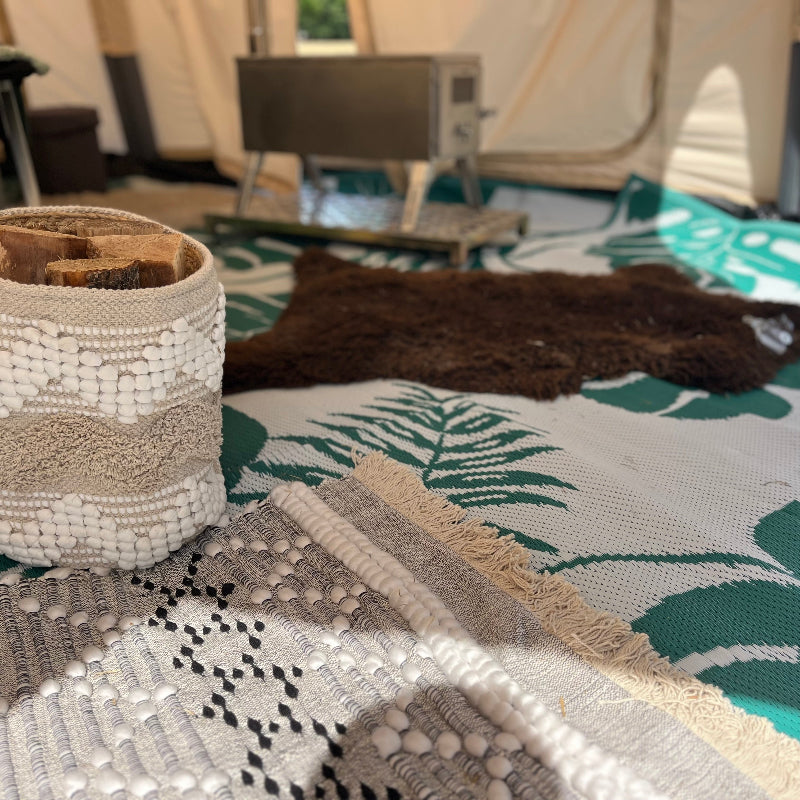 Textile items including a woven basket and patterned fabric on a surface with a blurred background.