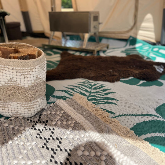 Textile items including a woven basket and patterned fabric on a surface with a blurred background.
