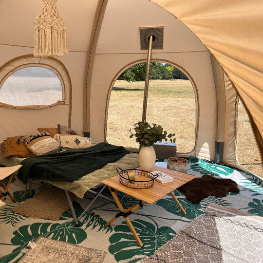 Interior of a 5m Glawning AIR tent with a table, pillows, and decorative elements.
