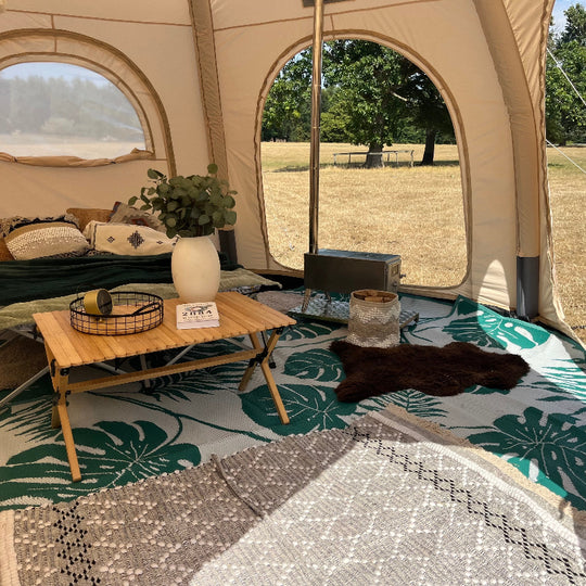5m Glawning tent interior with a small table, rug, and decorative items on a grassy outdoor setting.