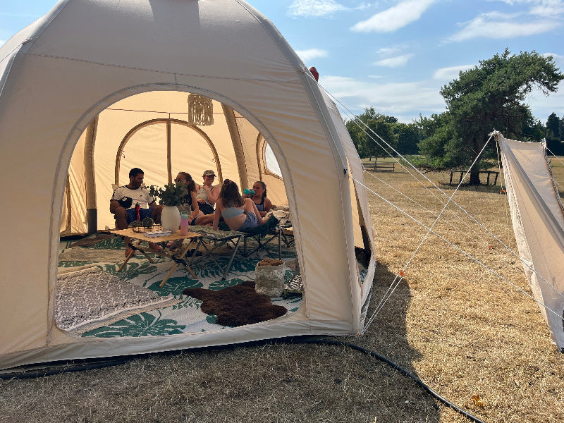 People sitting inside a 5m Glawning AIR tent with a scenic outdoor background