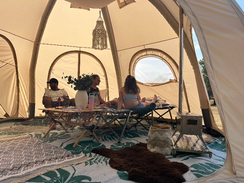 People sitting inside a 5m Glawning AIR tent with a table and chairs.