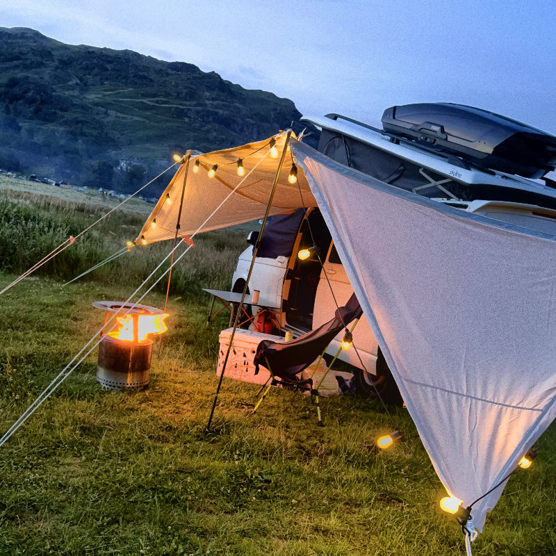 Camping scene with a Glanopy by Glawning, outdoor furniture, and a fire pit in a natural setting.